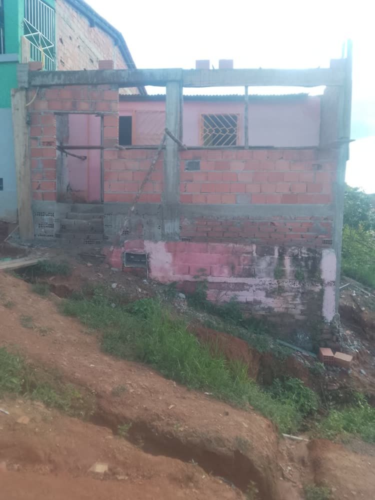 Casa em construção com paredes de tijolo, pilares e escoras
